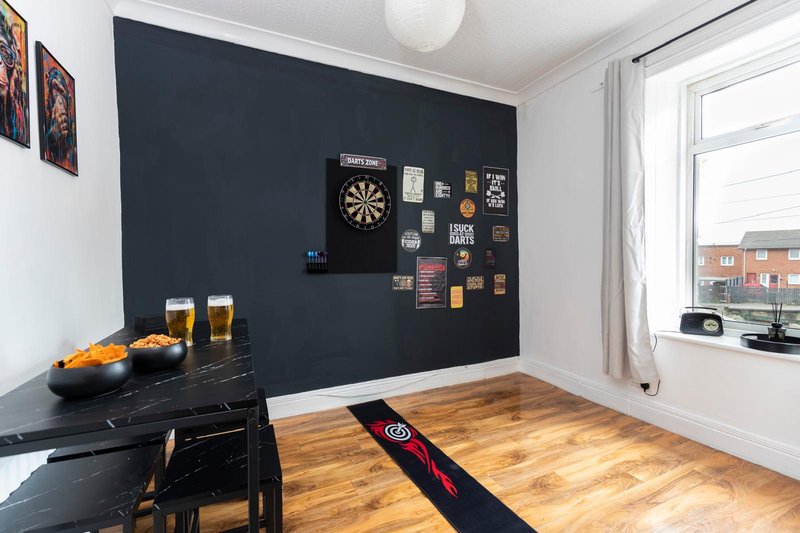 Game room with dartboard, black feature wall, wooden flooring and counter with beer glasses