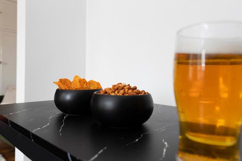 Black marble table with snack bowls and glass of beer in modern interior