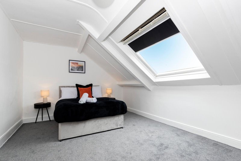 Attic bedroom with skylight, double bed, bedside lamps and framed artwork