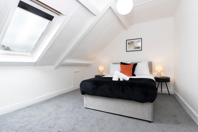 Bright attic bedroom with sloped ceiling, skylight, double bed and bedside lamps