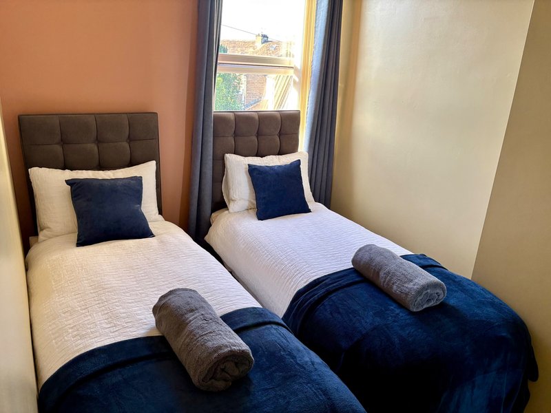 Twin bedroom with two single beds, navy blue bedding, and window with natural light
