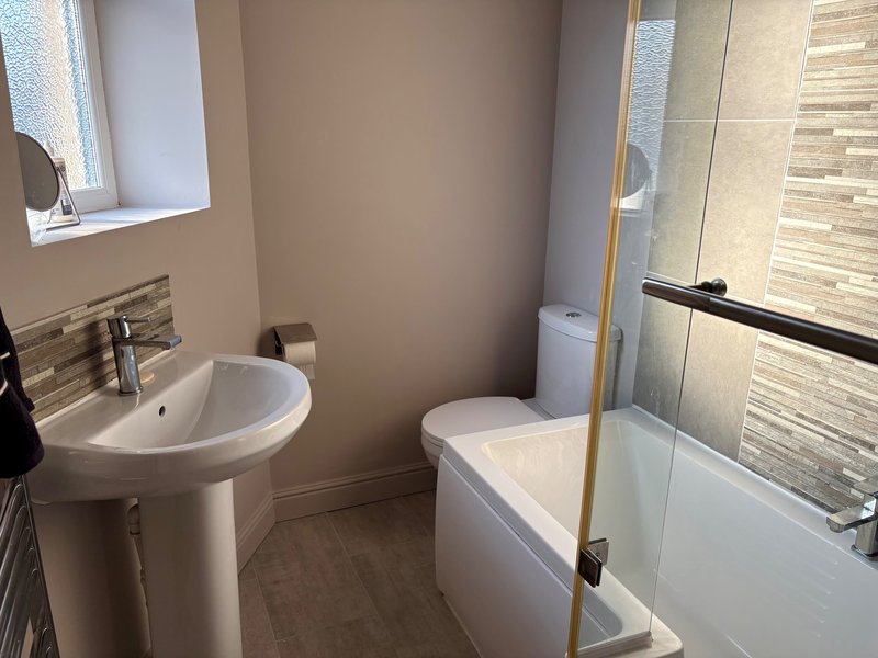 Modern bathroom with pedestal sink, bathtub, glass shower enclosure and window