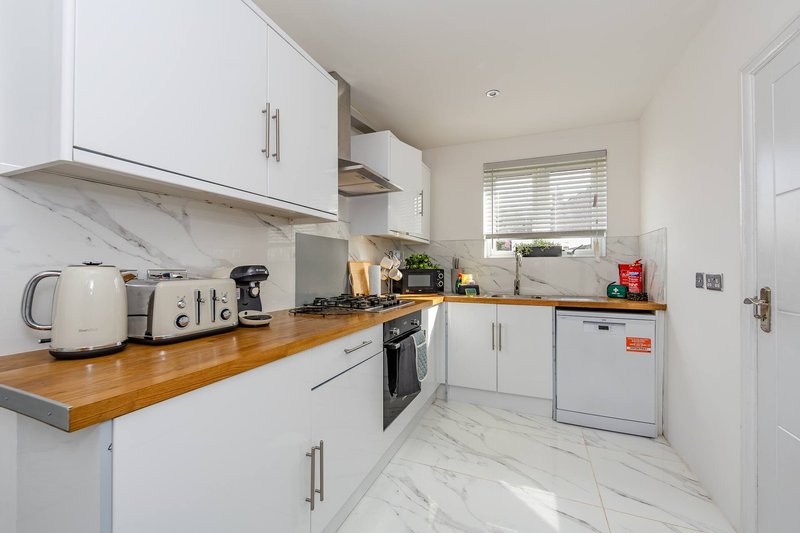 Modern kitchen with white cabinets, wooden countertop, stainless steel appliances and marble flooring