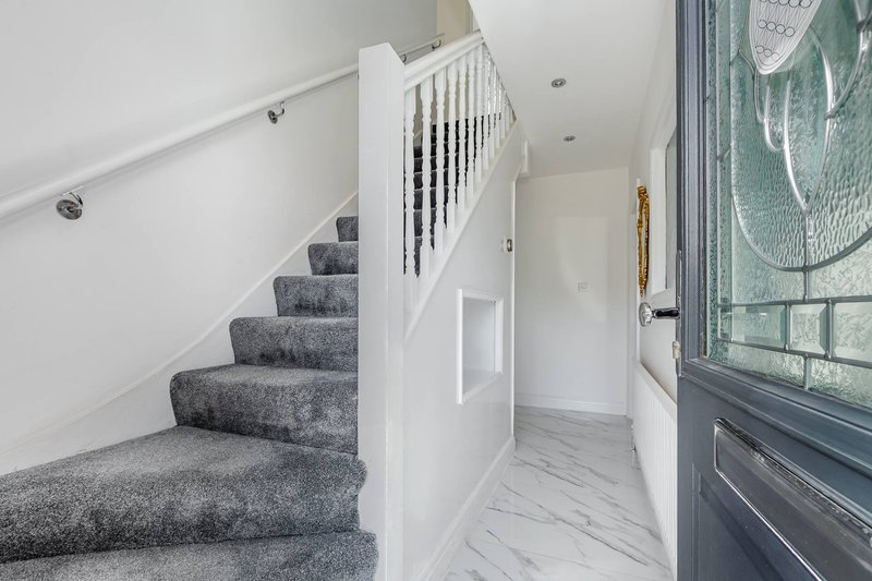 Modern hallway with carpeted staircase, white balustrade, wooden flooring and window