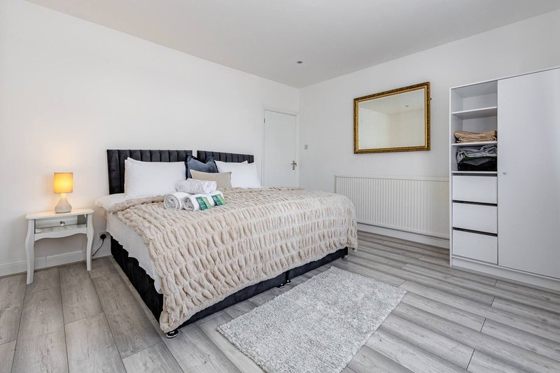 Modern bedroom with double bed, bedside table, lamp, and white wardrobe