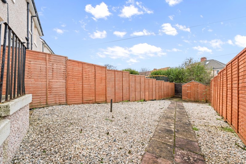 Enclosed outdoor patio area with gravel ground, wooden fencing and brick edging