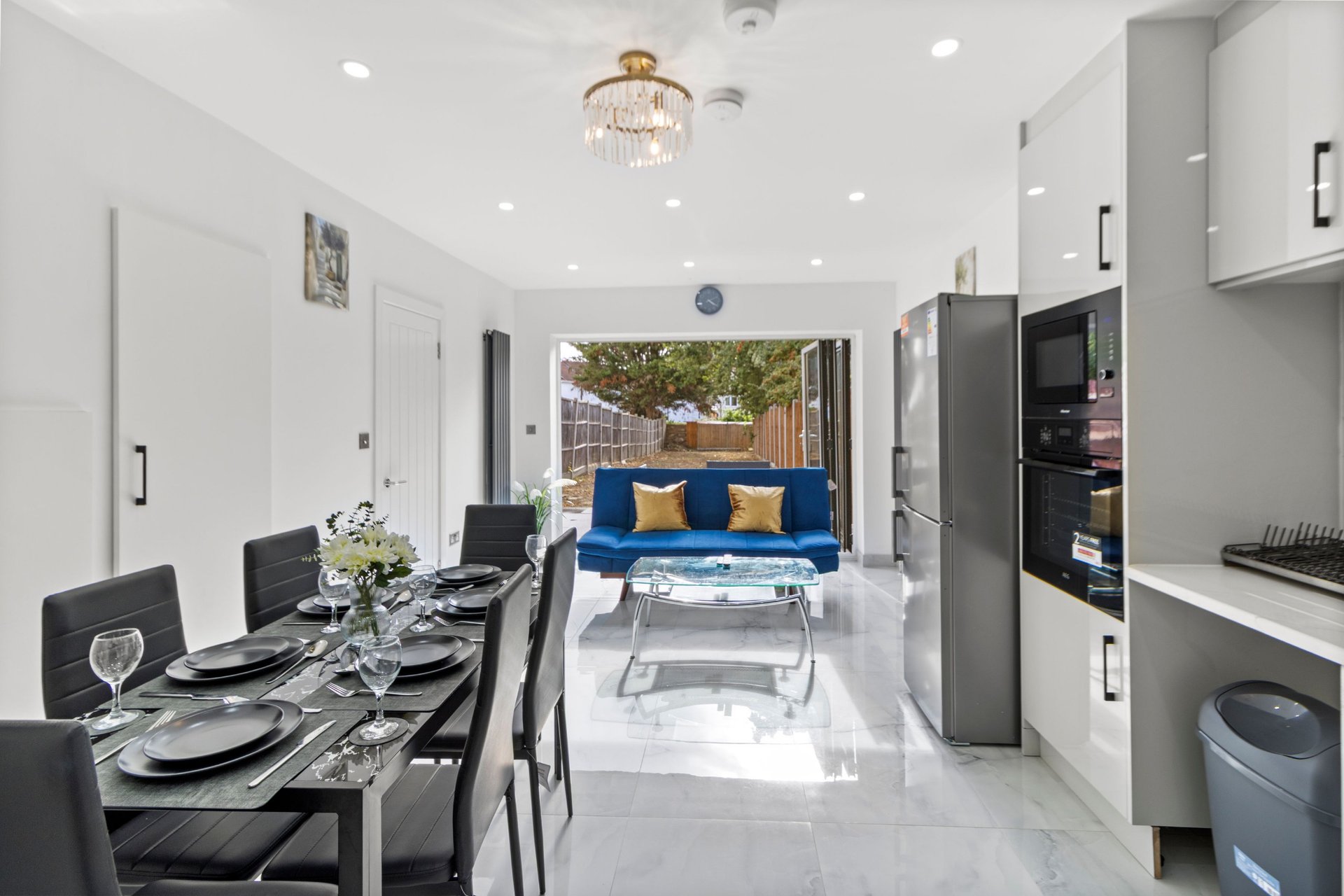 Open-plan kitchen and living area with dining table, blue sofa, and garden view