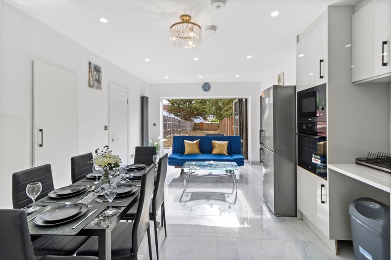 Open-plan kitchen and living area with dining table, blue sofa, and garden view