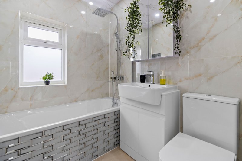Modern bathroom with bathtub, white sink, toilet, mirror and window