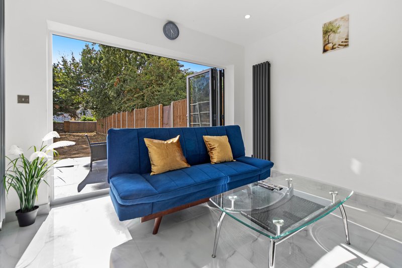 Modern living room with blue sofa, glass coffee table, potted plant and garden view