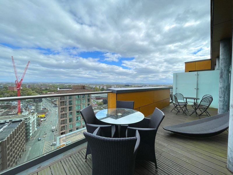 High-rise balcony with dining table, chairs, and city views over urban landscape