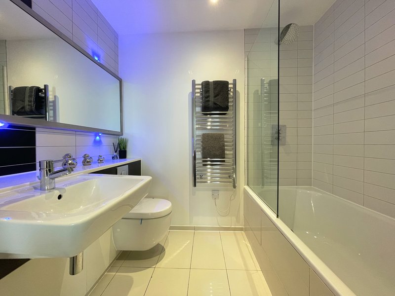 Modern bathroom with white sink, toilet, heated towel rack, and shower enclosure
