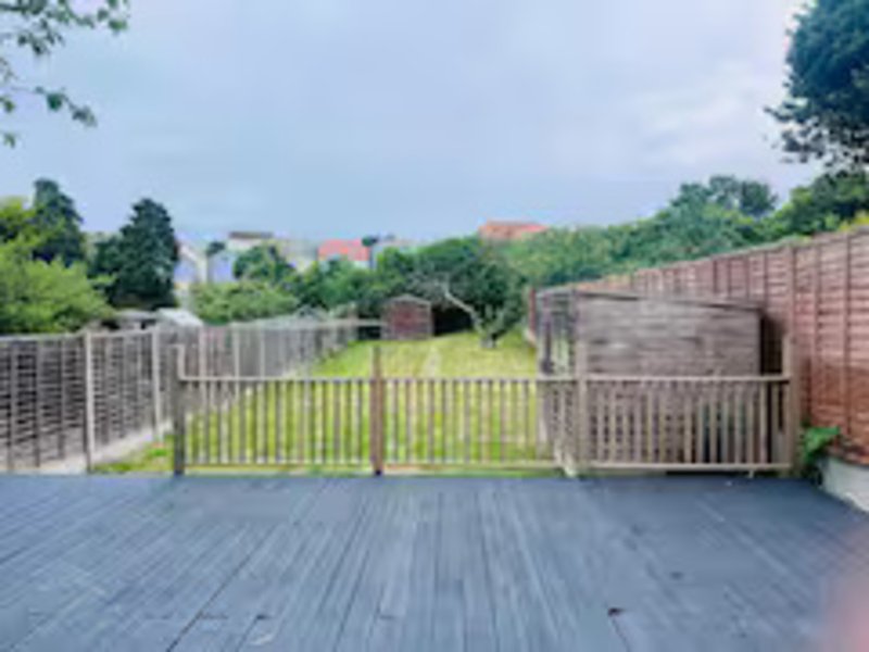 Rooftop decking with wooden railings, garden views and brick boundary walls