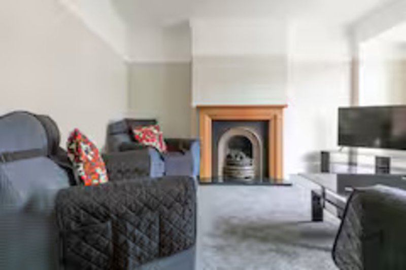 Living room with dark sofas, fireplace, TV, and decorative cushions