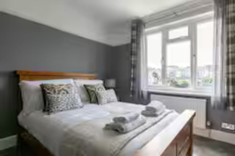 Modern bedroom with double bed, grey walls, patterned cushions and garden view