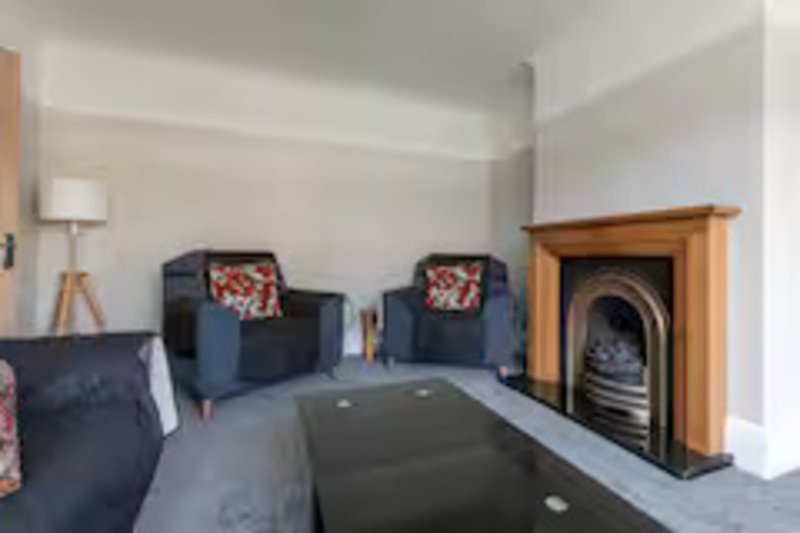 Spacious living room with two armchairs, fireplace, pool table and modern furnishings