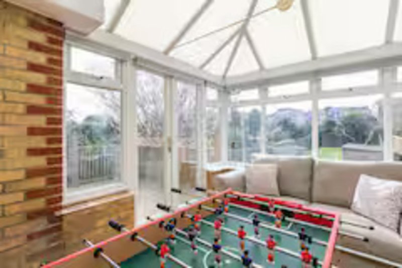 Conservatory with foosball table, seating area, brick wall and garden views