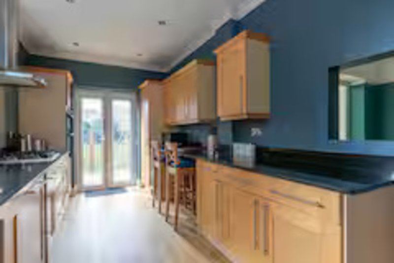 Modern kitchen with wooden cabinets, black countertops, blue walls and island seating