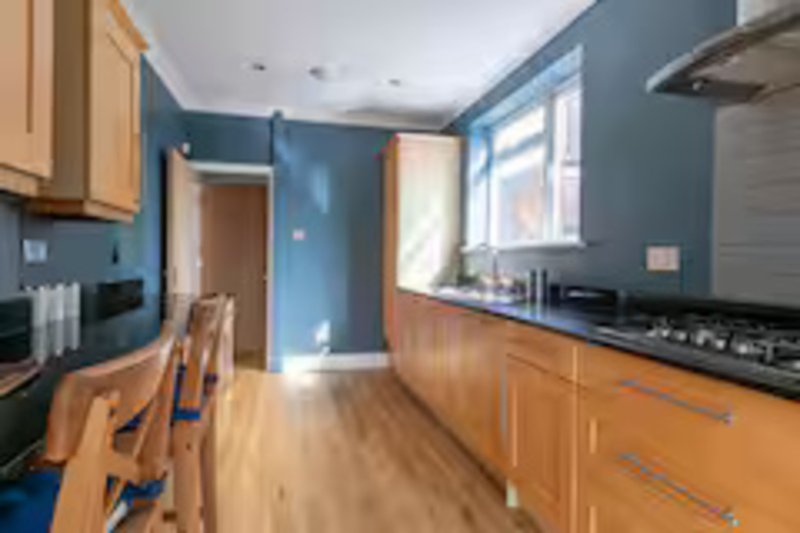 Modern kitchen with blue walls, wooden cabinets, gas hob and bright windows