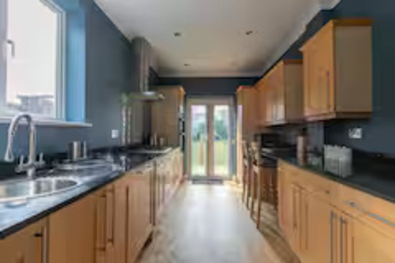 Modern kitchen with wooden cabinets, black countertops, stainless steel appliances and glazed doors