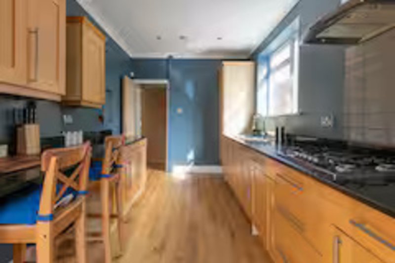 Galley kitchen with wooden cabinets, blue walls, dining chairs and gas cooktop