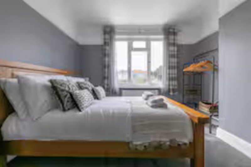 Modern bedroom with double bed, grey walls, patterned curtains and window view
