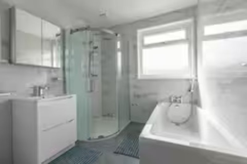 Modern bathroom with white vanity, curved shower enclosure, bathtub and windows