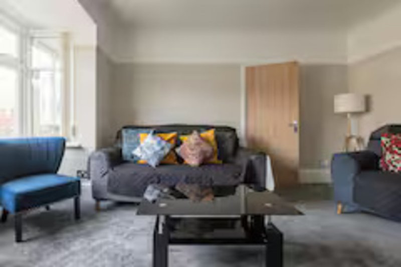 Living room with gray sofas, colorful cushions, black coffee table, and window