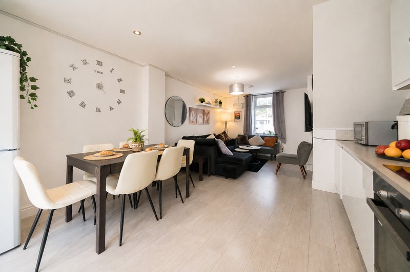 Open-plan kitchen, dining and living area with light wood flooring and modern furnishings