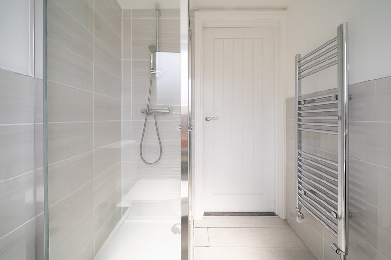 Modern bathroom with walk-in shower, glass screen, heated towel rail and white door