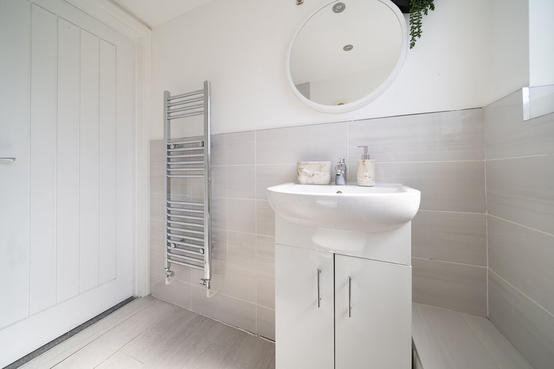 Modern bathroom with white vanity, round mirror, towel rail and neutral tile walls