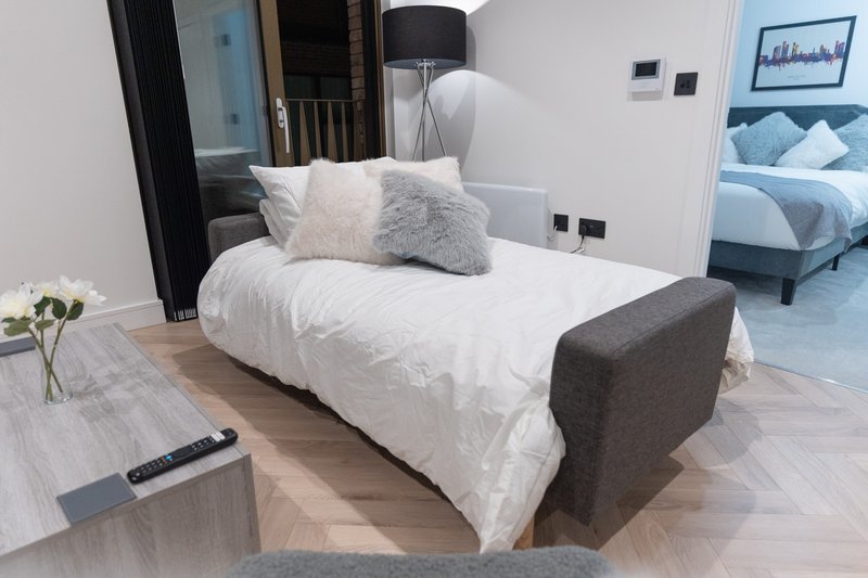 Modern bedroom with double bed, white bedding, grey headboard and decorative pillows