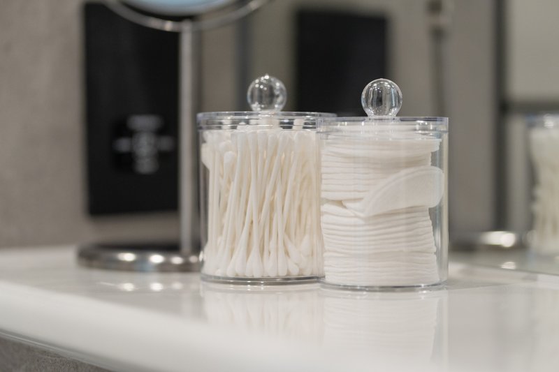 Bathroom counter with clear storage containers holding cotton swabs and pads