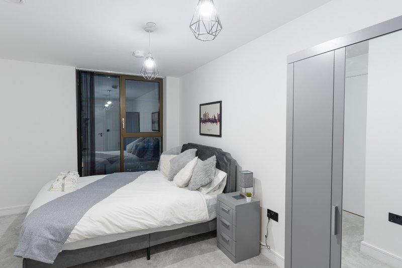 Modern bedroom with double bed, grey bedding, pendant lights and built-in wardrobe