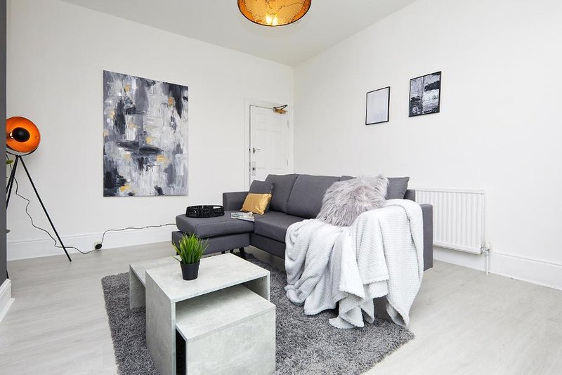 Modern living room with grey corner sofa, white coffee table, abstract wall art and pendant lamp