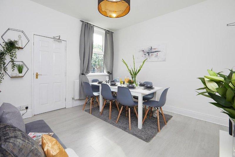 Modern dining room with white table, grey chairs, wooden accents and potted plants