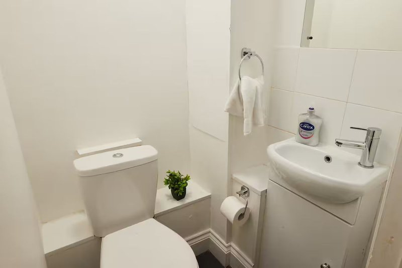 Small bathroom with toilet, sink, towel rail and white tile walls