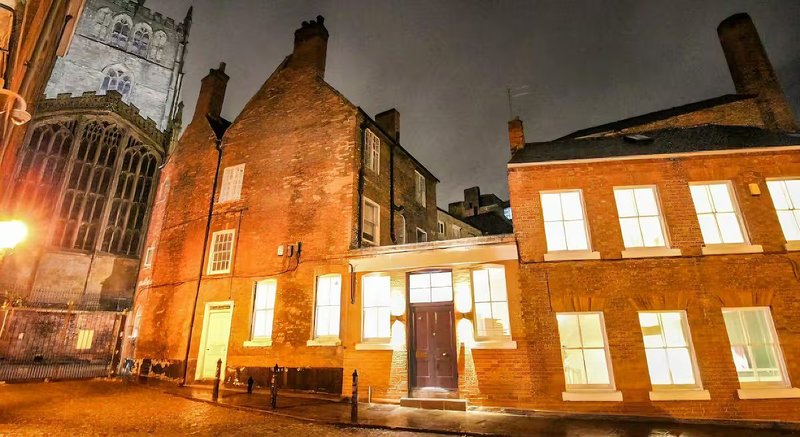 Historic brick buildings lit up at night, traditional architecture with multiple windows and chimneys