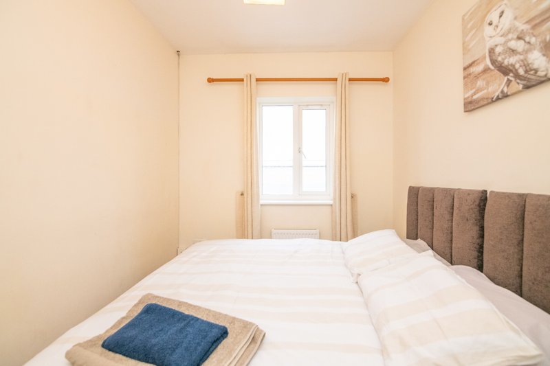Bright bedroom with double bed, white bedding, upholstered headboard and glass door