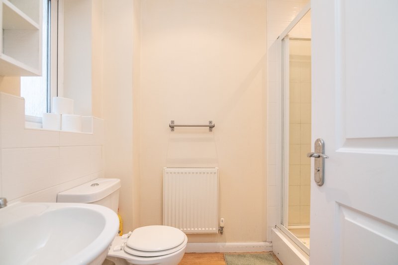 Small bathroom with toilet, sink, radiator and shower cubicle