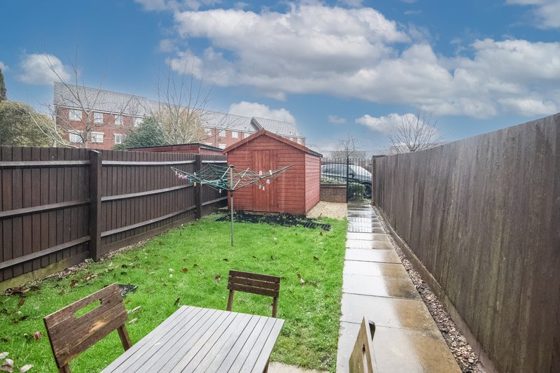 Enclosed garden with decking, lawn, wooden benches and red garden shed