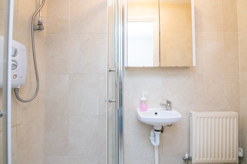 Modern bathroom with shower enclosure, wall-mounted sink, mirror cabinet and radiator