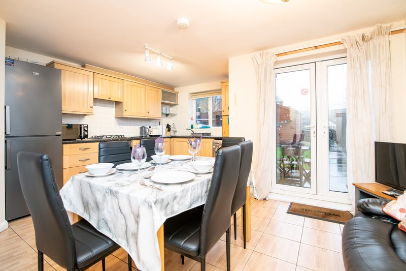 Open-plan kitchen and dining area with wooden cabinets, dining table, and garden doors