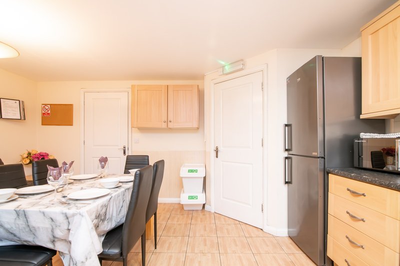 Kitchen and dining area with wooden cabinets, stainless steel refrigerator, dining table and chairs