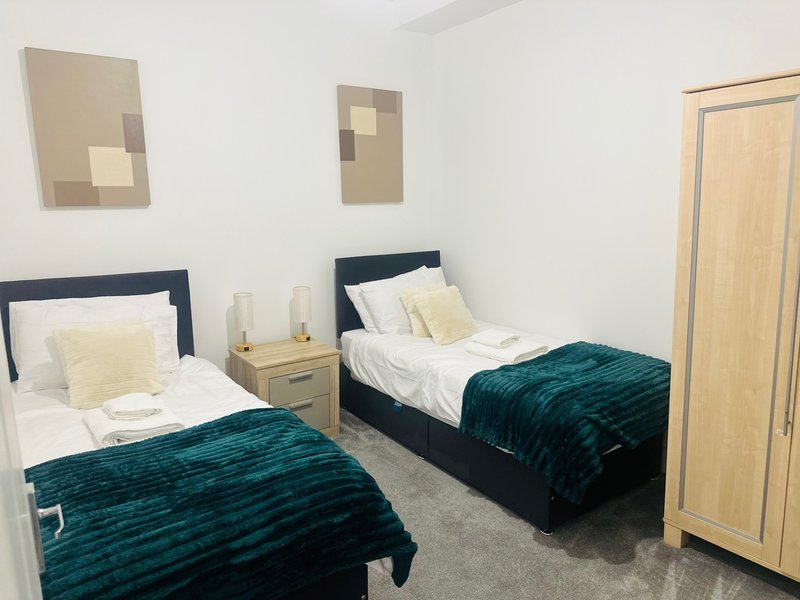 Twin bedroom with dark headboards, teal throws, wooden nightstand, and wall art