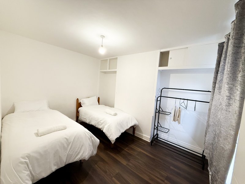 Twin bedroom with two single beds, wooden flooring, built-in storage and ceiling light
