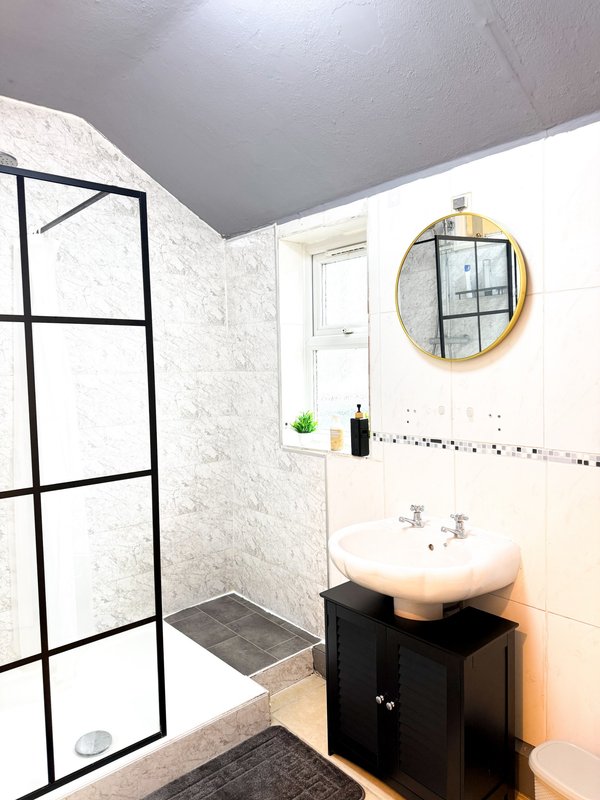 Modern bathroom with shower enclosure, round mirror, and black vanity sink