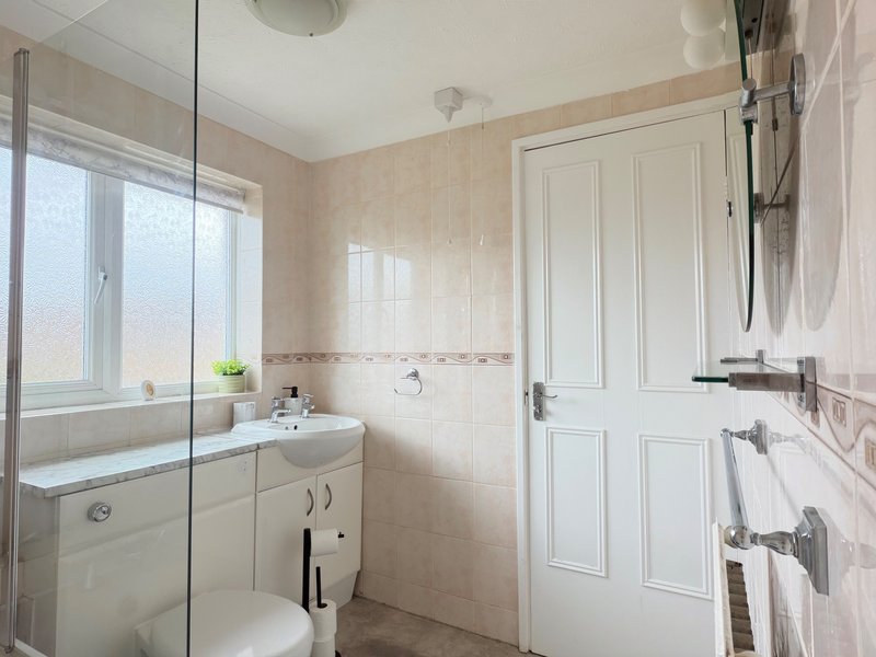 Modern bathroom with shower enclosure, vanity sink, toilet, and heated towel rail