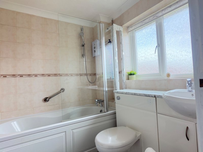 Bathroom with bathtub, shower screen, toilet, sink and frosted window