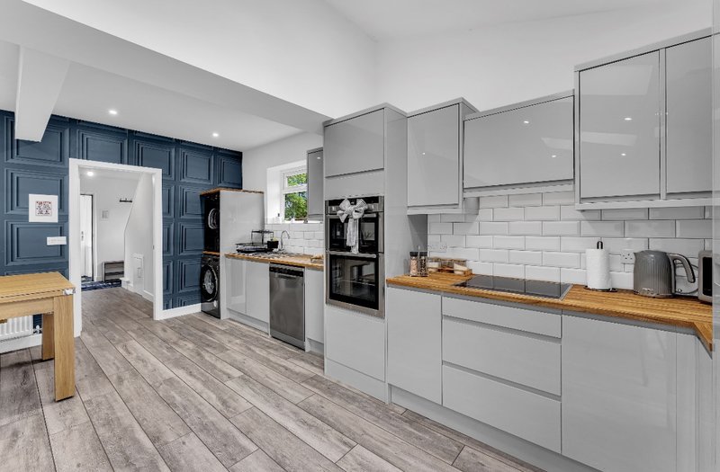 Modern kitchen with grey cabinetry, white subway tile splashback, wooden countertops and stainless steel appliances